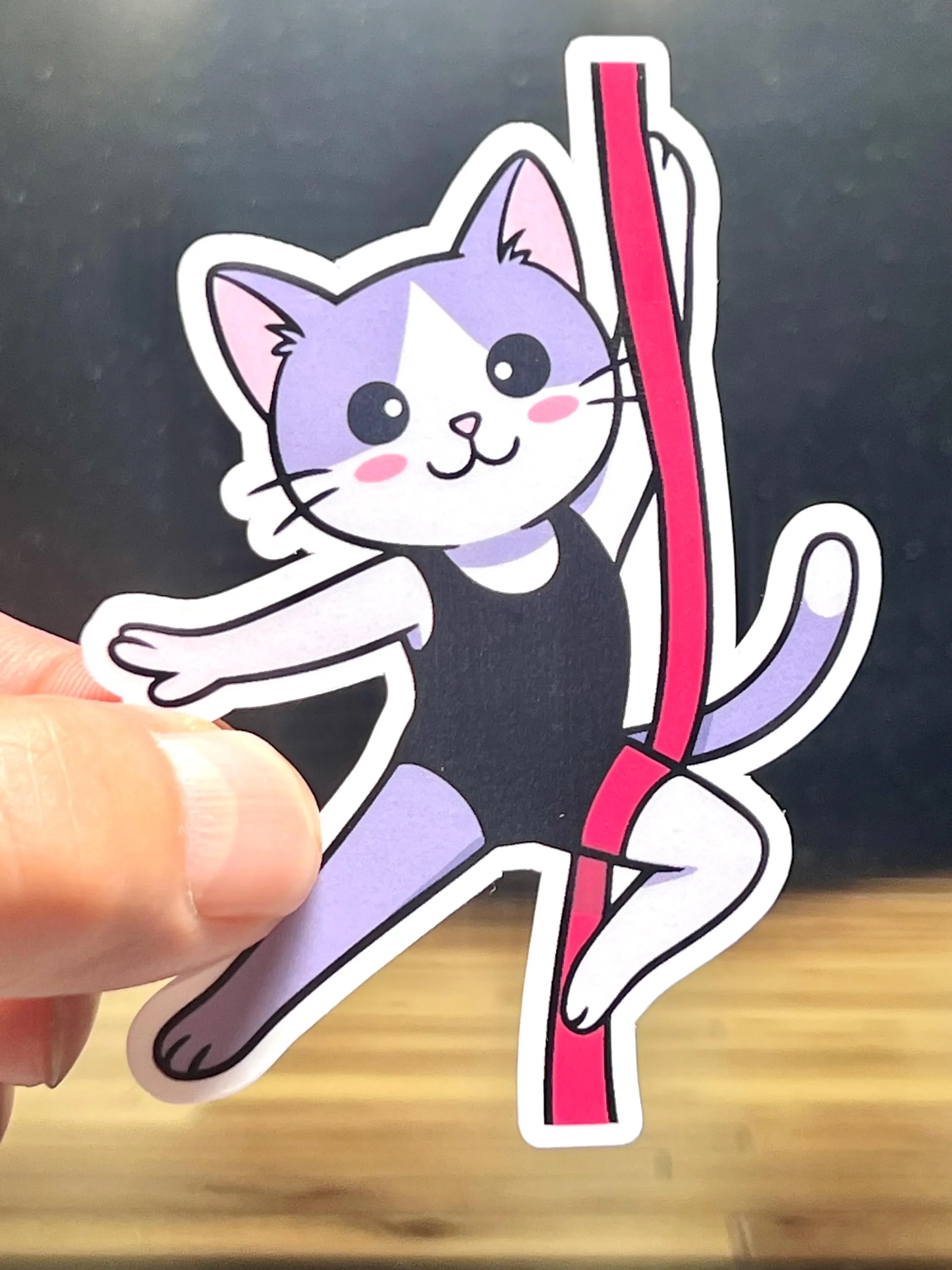 Sticker of a a cat performing on aerial silks.