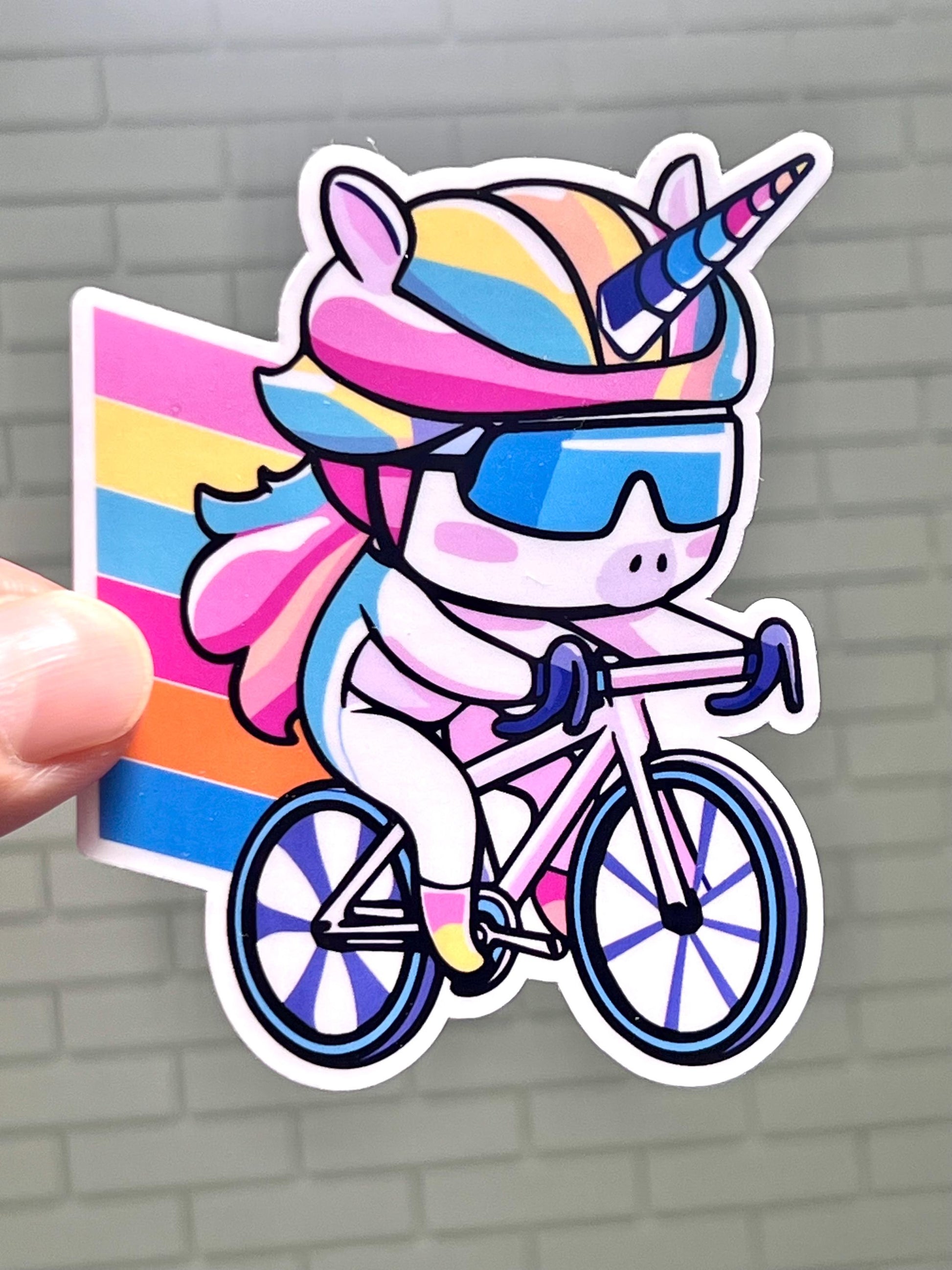 A colorful sticker of a cartoon unicorn wearing sunglasses and riding a bicycle with a rainbow background.