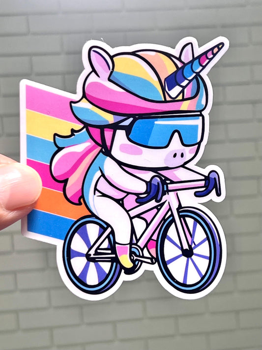 A colorful sticker of a cartoon unicorn wearing sunglasses and riding a bicycle with a rainbow background.