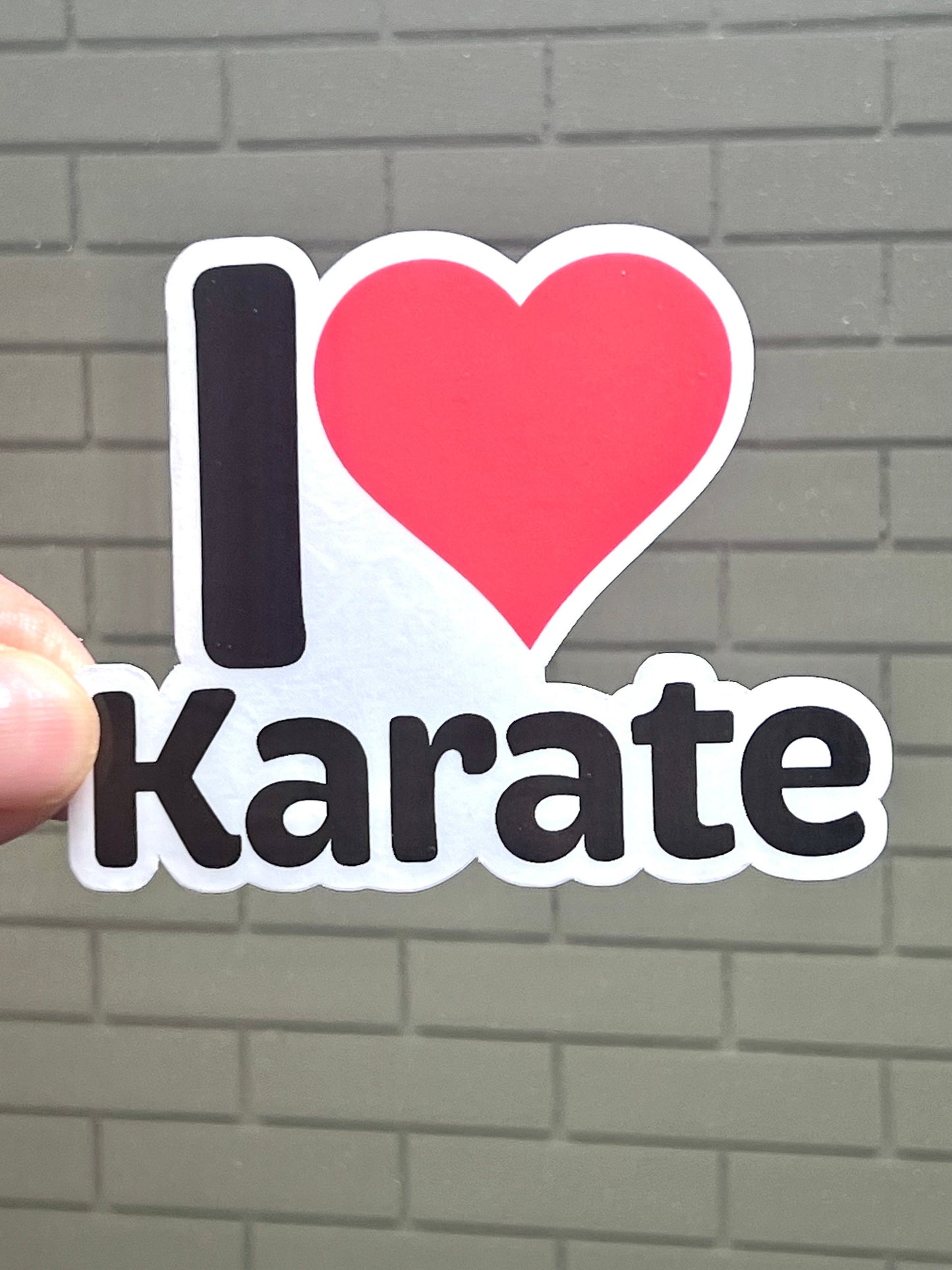 A vinyl sticker with the text 'I LOVE KARATE' and a heart symbol representing the word 'love'. The sticker is primarily black with red and white text.