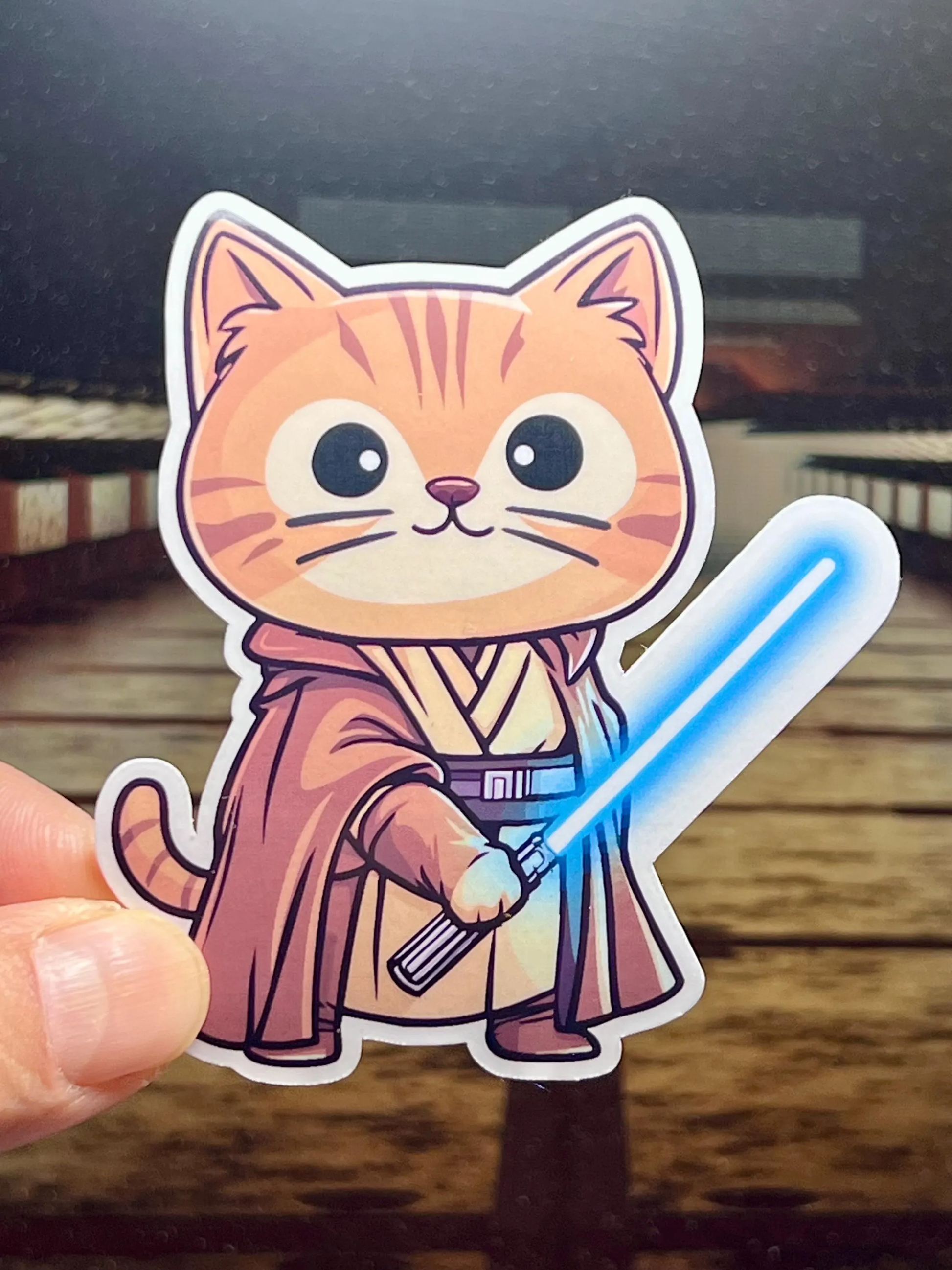 A vinyl sticker of a jedi cat and holding a lightsaber.