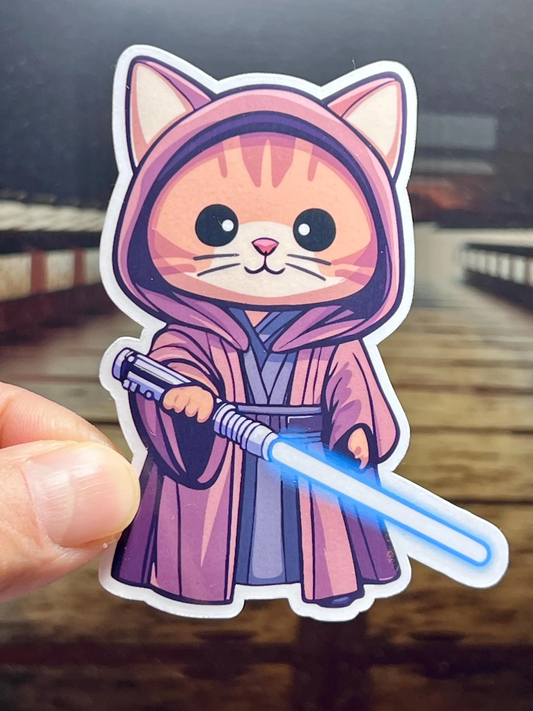 A vinyl sticker of a jedi cat carrying a blue lightsaber