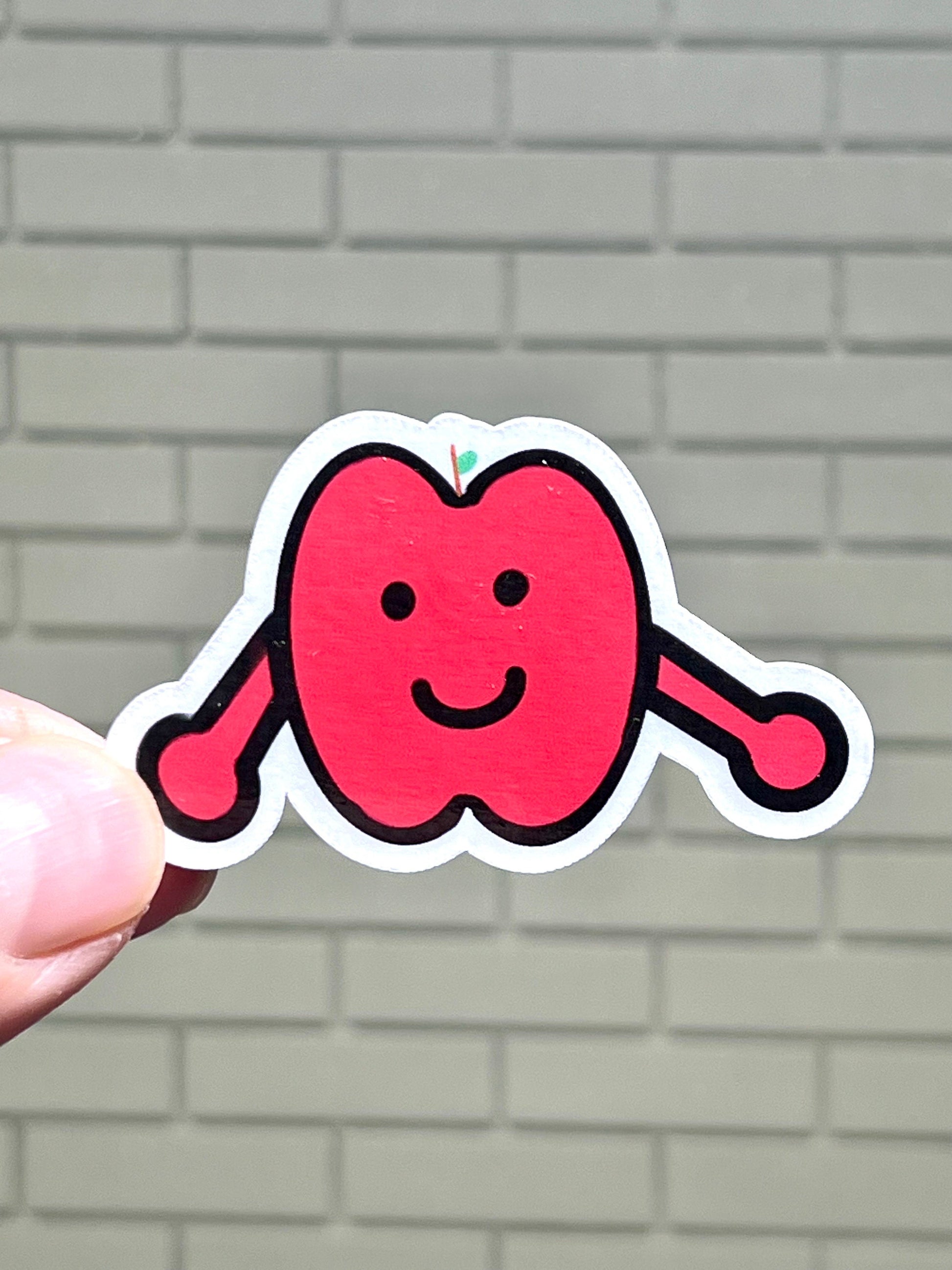 A sticker of a cartoon apple with a smiling face and a tiny stem