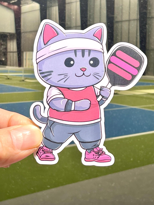 A vinyl sticker of a cute pickleball cat carrying pickleball paddle.