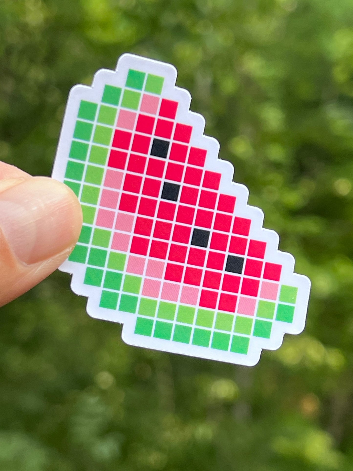 A die-cut vinyl sticker with a pixel art design of a watermelon slice